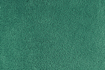 Green suede leather texture with embossed shabby spotted pattern. Structure of fleecy cloth surface, decorative upholstery fabric, home decor and garment. Wallpaper, background, backdrop.