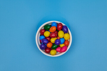 Chewing gum balls of different colors in shiny earthenware containers with a homogeneous colored background for placing text