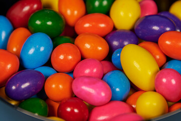 Chewing gum balls of different colors in shiny earthenware containers with a homogeneous colored background for placing text