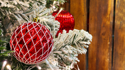Red Christmas Balls Are Hanging On A Snowy Christmas Tree With A Wooden Background, Creating A Festive Holiday Scene