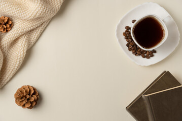 Cup of coffee with coffee beans, books and scarf on beige background. Copy space. Flat lay, top view