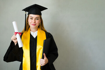 Proud young woman holding her diploma and smiling at her graduation ceremony, looking forward to a bright future filled with opportunities