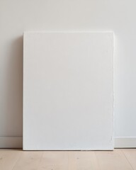 Blank white square canvas leaning against the wall on an empty floor, viewed from directly above, sharp focus with clean, uncluttered background, ideal for artwork or design customization.

