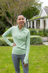 Smiling woman in activewear enjoying outdoor exercise in lush garden