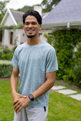 Smiling young man enjoying sunny day in garden, wearing casual outfit