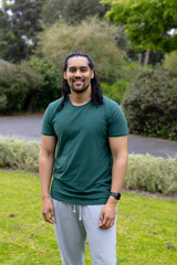 Smiling man standing in park wearing casual clothes, enjoying outdoor greenery