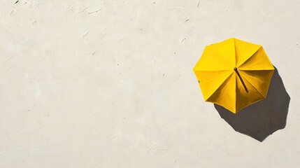   Overhead view of a yellow umbrella on a white wall with a person's shadow