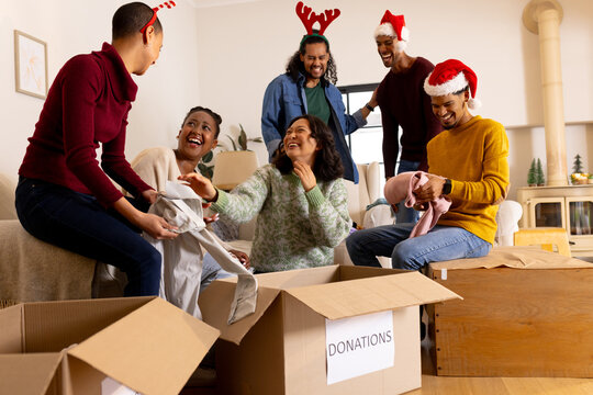Christmas time, young multiracial friends laughing while sorting donations at home