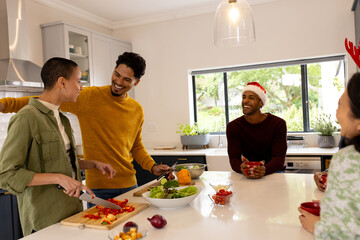 Christmas time, preparing festive meal in kitchen, multiracial friends laughing at home