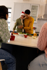 Christmas time, multiracial friends laughing and cooking together in kitchen at home