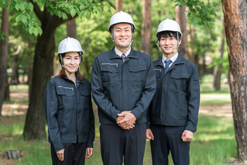 森林の中にいる林業・土木業の作業着姿の男女の作業員
