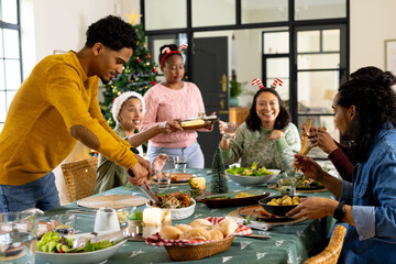 Sharing laughter, multiracial friends celebrating christmas dinner together, at home