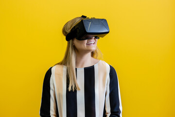 Young woman wearing a virtual reality device, viewing a virtual world in augmented reality. Depreciated virtual device, augmented reality visualisation. Head-mounted display to see a digital land