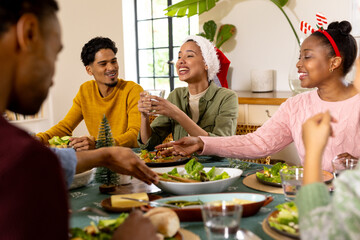 Christmas time, young multiracial friends enjoying festive holiday meal together, at home