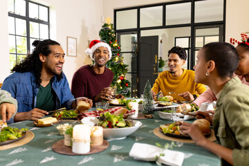 Multiracial friends enjoying festive christmas meal together, at home