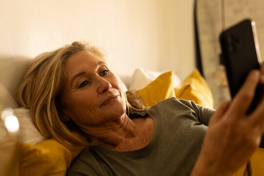 Relaxing at home, senior woman using smartphone, enjoying leisure time