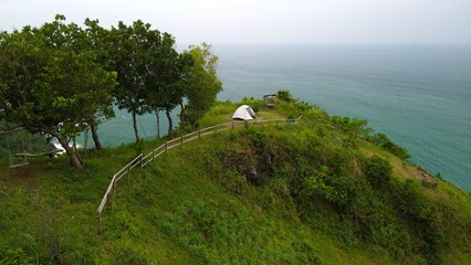 Aerial view drone camera 4k A man camping in a Hills and cliffs bordering the seaside and beaches with beautiful waves in Jerit Hill Kebumen central java Indonesia