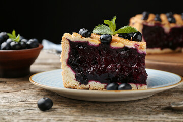 Slice of homemade blueberry pie on wooden table, closeup