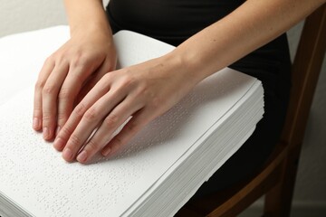 Blind woman reading book written in Braille indoors, closeup