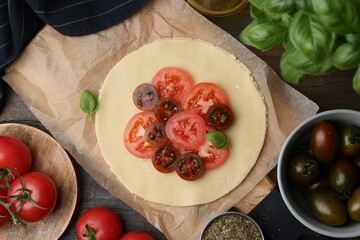 Raw galette with tomato and basil on wooden table, flat lay
