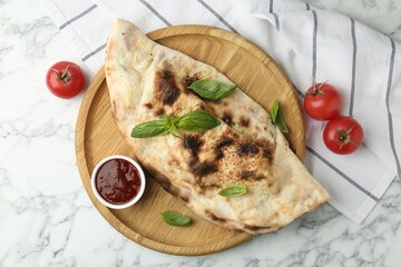 Delicious calzone served on white marble table, top view