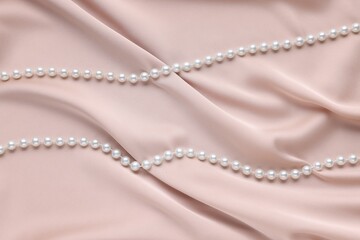Elegant pearl necklace on beige fabric, top view