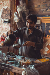 Pakistani street vendor pouring chai tea into cups in his roadside tea stall