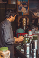 Pakistani street vendor preparing chai tea in his roadside tea stall