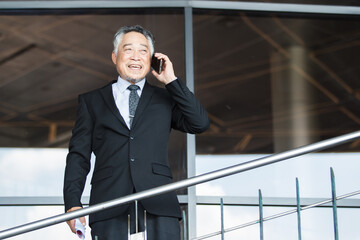 Portrait of Asian senior businessman walking in the office building.