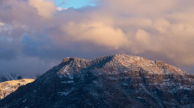 Time lapse over Y Mountain covered in snow over Provo during sunset as light fades and clouds move over the Wasatch range.