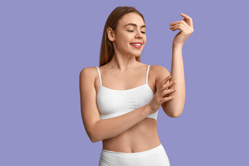 Beautiful young happy woman after depilation of arms on purple background