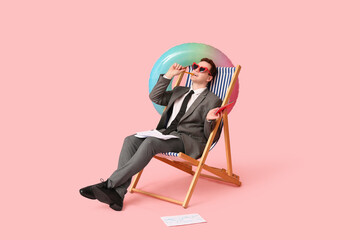 Office worker sitting on deck chair with inflatable ring and papers while dreaming about vacation...