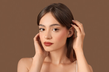 Young woman with beautiful eyebrows on brown background