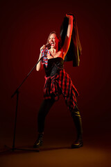 Fototapeta premium Beautiful female singer with microphone on dark red background