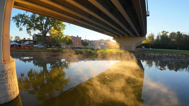 Ethereal sunrise under bridge and over steaming waters.

