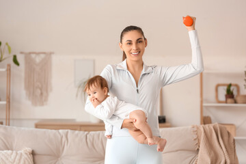 Obraz premium Sporty young mother with her little baby and dumbbell at home