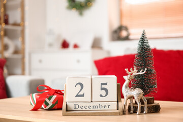 Cube calendar with date of Christmas, decor and gift on table in living room, closeup