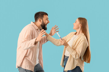 Happy young couple with pregnancy test on blue background
