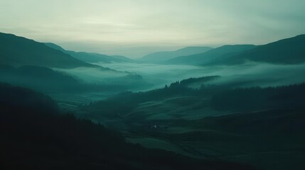 Fototapeta premium As dawn breaks, a serene mist envelops the valley, creating a tranquil atmosphere. The soft hues of morning light illuminate the rolling hills and dense foliage.