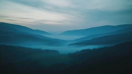 Fototapeta premium As dawn breaks, a serene mist envelops the valley, creating a tranquil atmosphere. The soft hues of morning light illuminate the rolling hills and dense foliage.