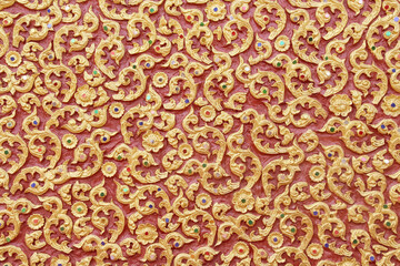 Traditional Thai art carving gold floral seamless patterns on red concrete temple wall background