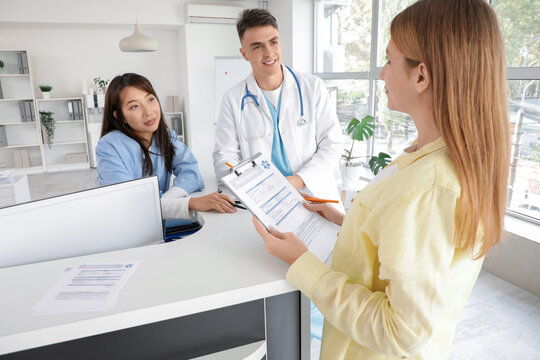 Medical intern working with patient and doctor at reception in clinic