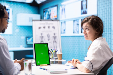 Physician discussing test results with a patient next to isolated mockup screen, presenting healthcare diagnosis during check up visit. Doctor discussing the treatment plan and advice.