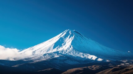 The iconic Mount Fuji is illuminated by the fading twilight, showcasing its snow-capped peak in the serene atmosphere. Wisps of clouds surround the majestic mountain, creating a tranquil view.