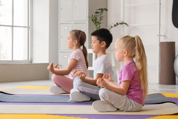 Cute little children meditating in gym