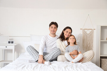 Little girl with her parents sitting in bedroom