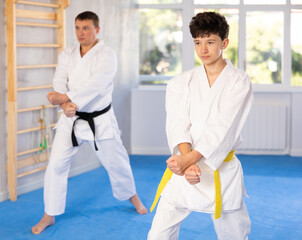 Fototapeta premium Active teenage male attendee of karate classes practicing kata in sports hall