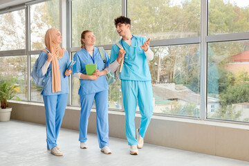 Medical students with backpacks and books near window at university