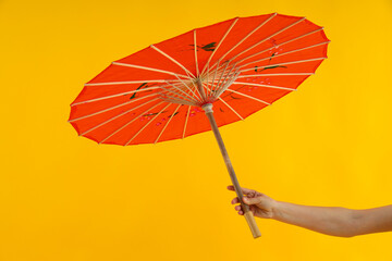 Red Japanese umbrella in hand on yellow background