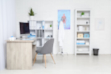 Blurred view of medical office with doctor's workplace and shelf units